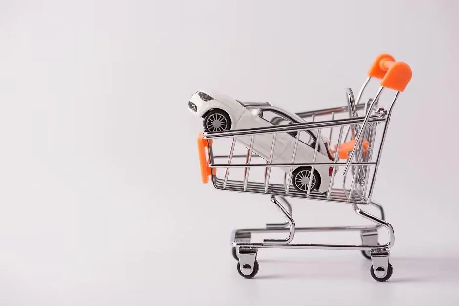 Toy car in a miniature shopping cart on a white background