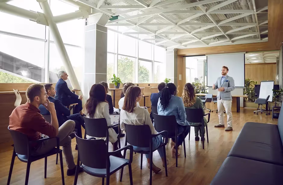 Presenter speaking to an audience of employees in a bright office hall