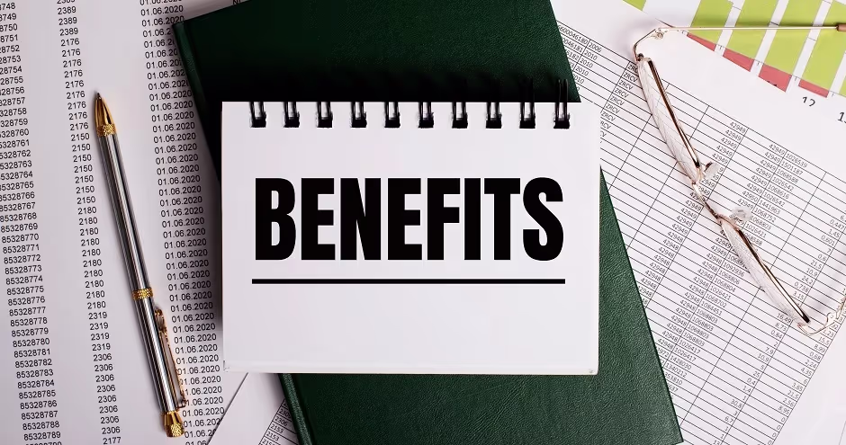 Notepad reading "BENEFITS" on top of financial spreadsheets with a pen and glasses