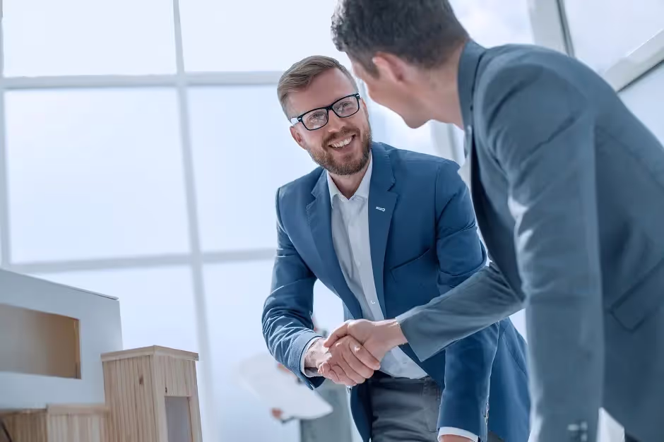 Two smiling businessmen shaking hands in a bright office