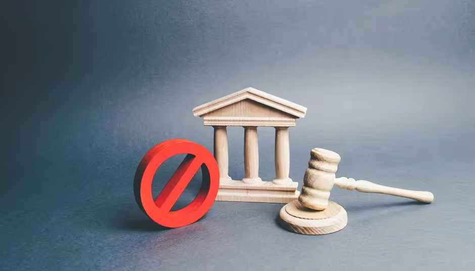 Red prohibition sign beside a courthouse model and a judge's gavel