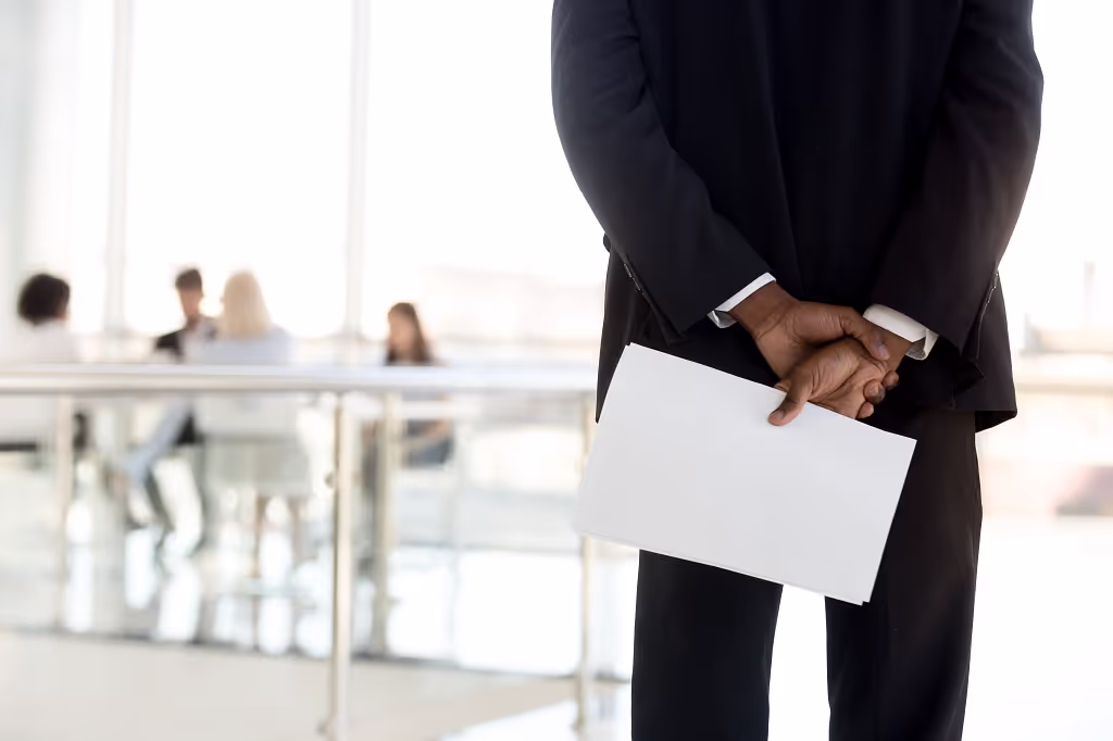 Businessman holding a sealed envelope behind his back in an office