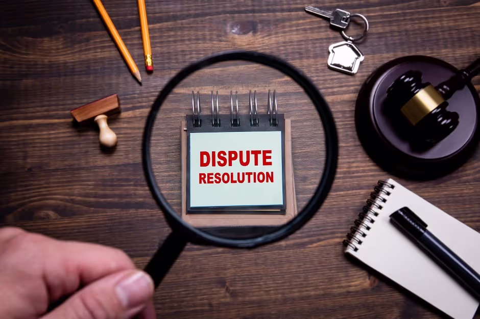 Magnifying glass over a notepad reading Dispute Resolution beside a gavel