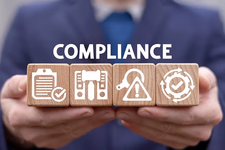 Hands holding wooden blocks with compliance icons under the word Compliance