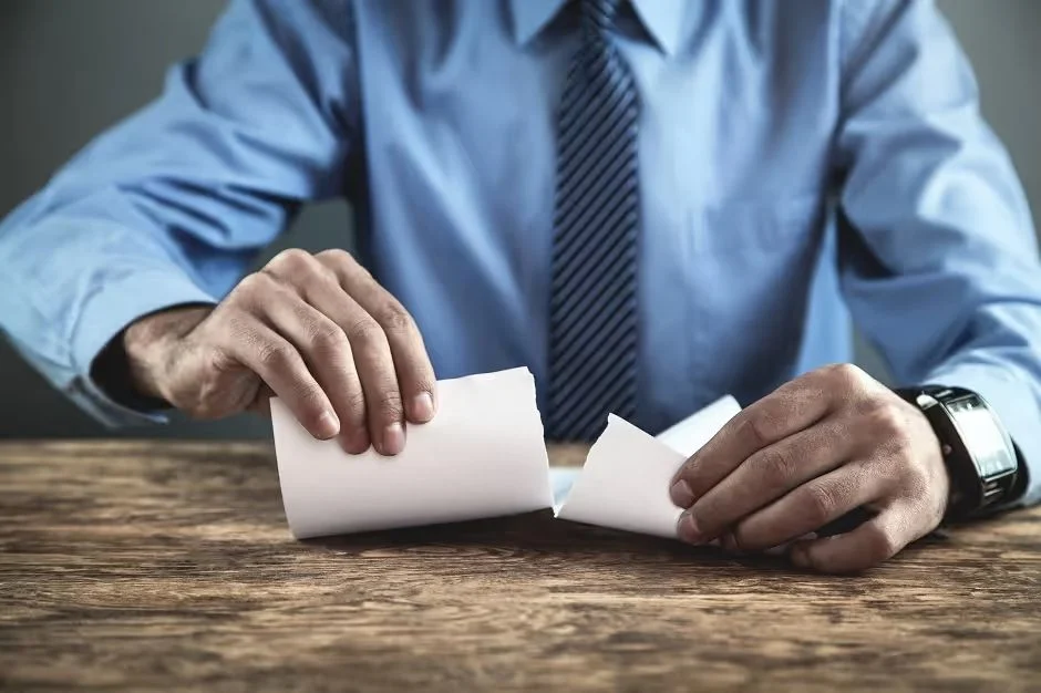 Businessman in a shirt and tie tearing up a paper contract