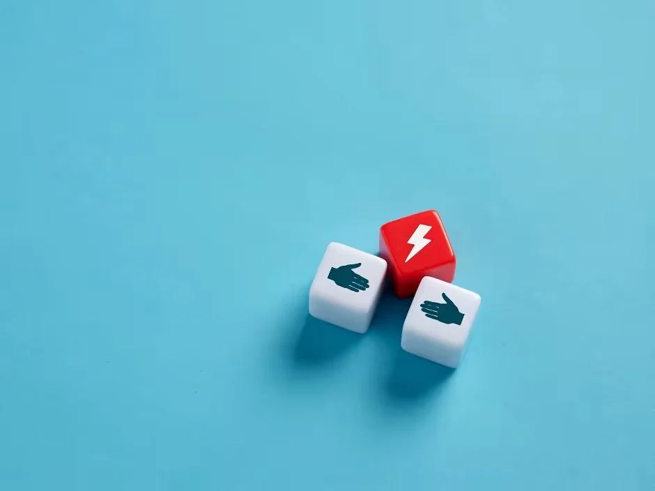 Two dice showing shaking hands and a red dice with a lightning bolt, symbolizing conflict