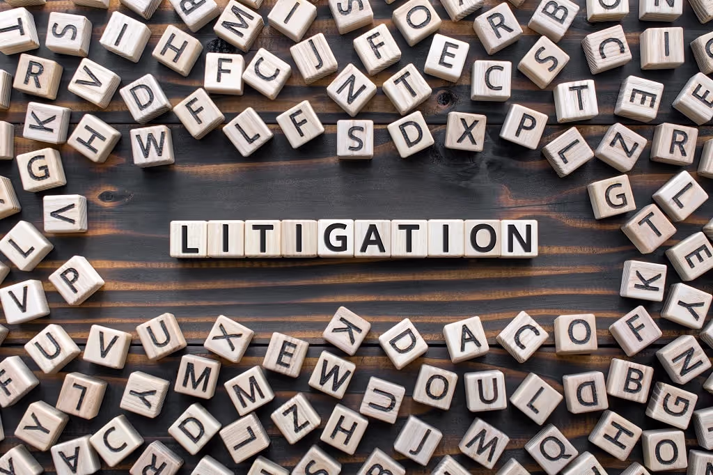 Wooden letter tiles spelling LITIGATION surrounded by scattered letters