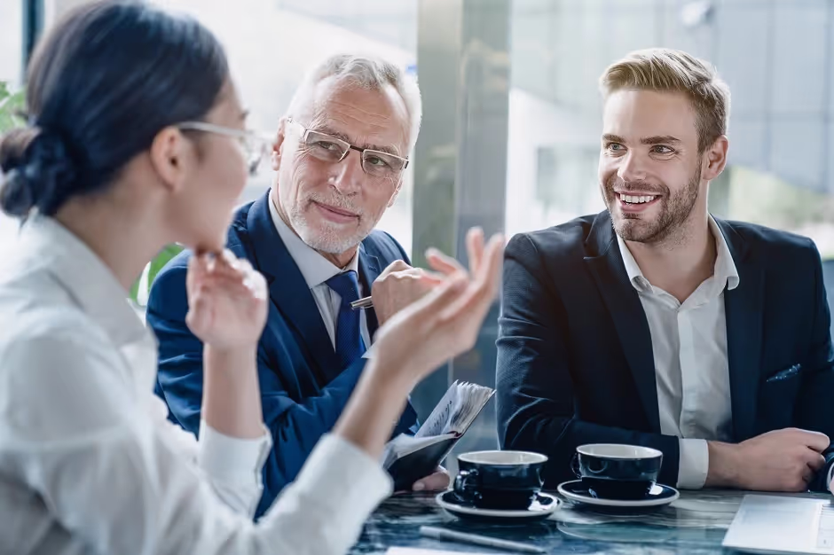 Three colleagues talking over coffee at a business meeting table
