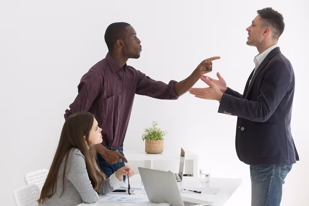 Two men arguing in an office while a female colleague looks on