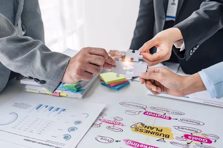 Business team joining puzzle pieces over a business plan diagram