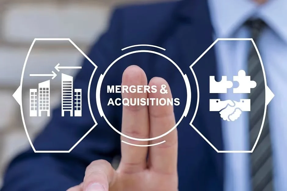 Hand touching a "Mergers & Acquisitions" graphic with buildings and handshake icons