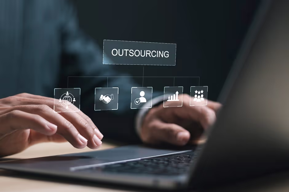 Hands typing on a laptop under an "OUTSOURCING" diagram of business icons