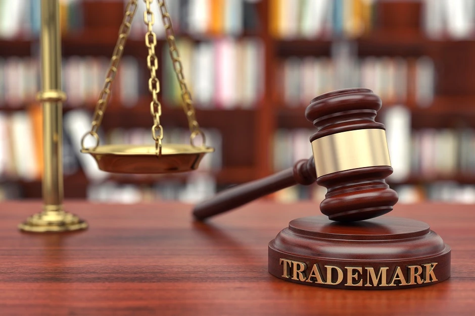 Judge's gavel on a block engraved "TRADEMARK" beside scales of justice