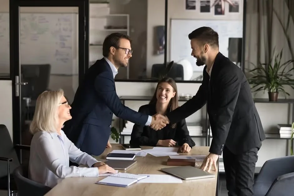 Business people shaking hands across a meeting table in a modern office