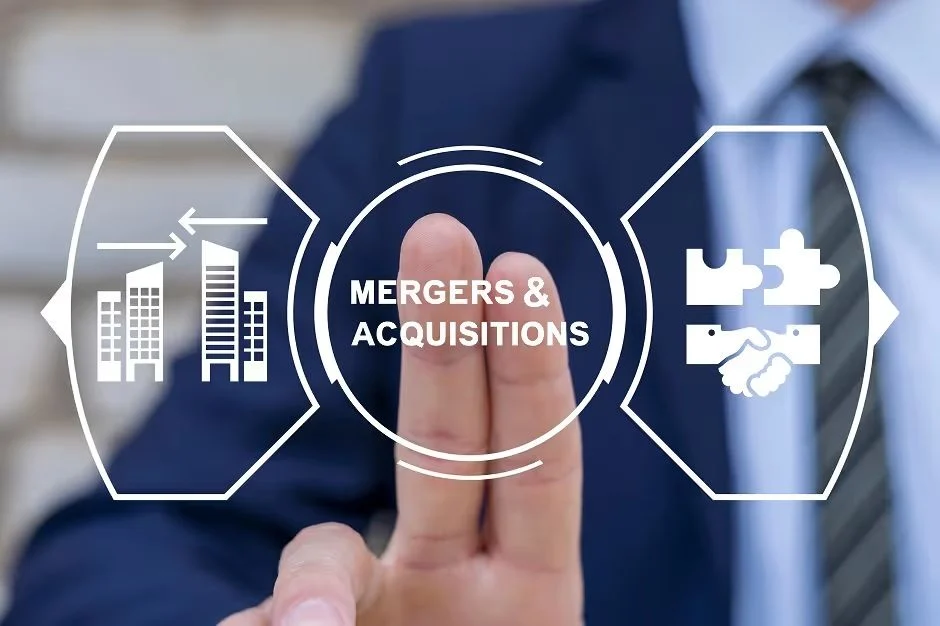Hand touching a "Mergers & Acquisitions" graphic with buildings and handshake icons
