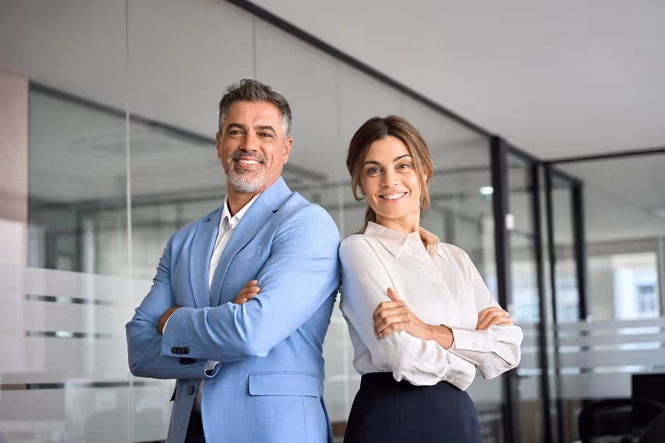 Confident businessman and businesswoman standing back to back with arms crossed